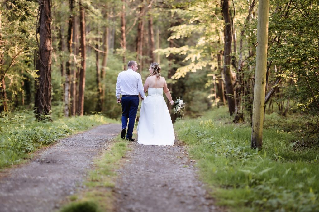 summer outdoor wedding photo in the forest. Bride and groom walking in the forest