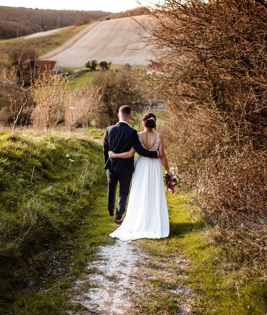 bride and groom walking together during the sunset in the countryside