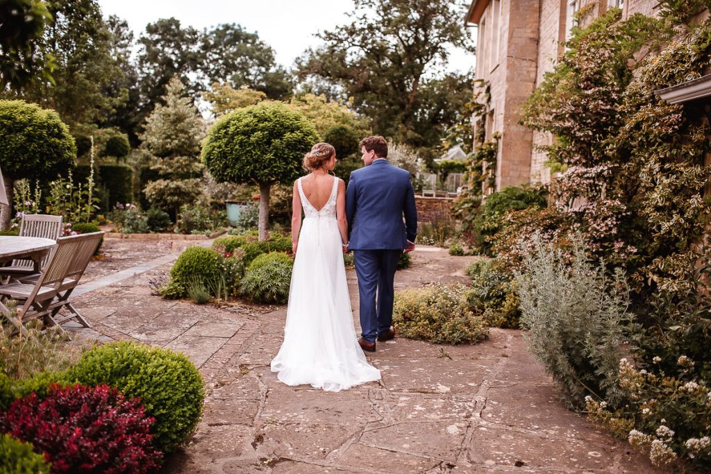 bride and groom walking through the garden in Cotswold