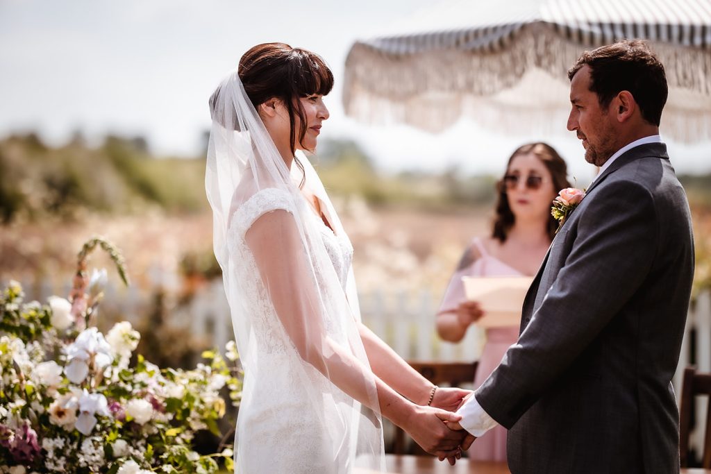 bride and groom holding their hands during the outdoor wedding ceremony