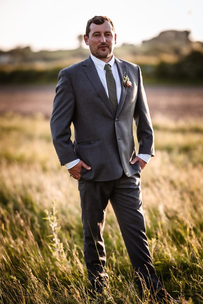 Natural and relaxed photos of groom standing in the field