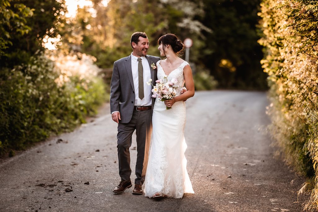 Sunset photos of bride and groom. Wedding couple during the golden hour walking in the road