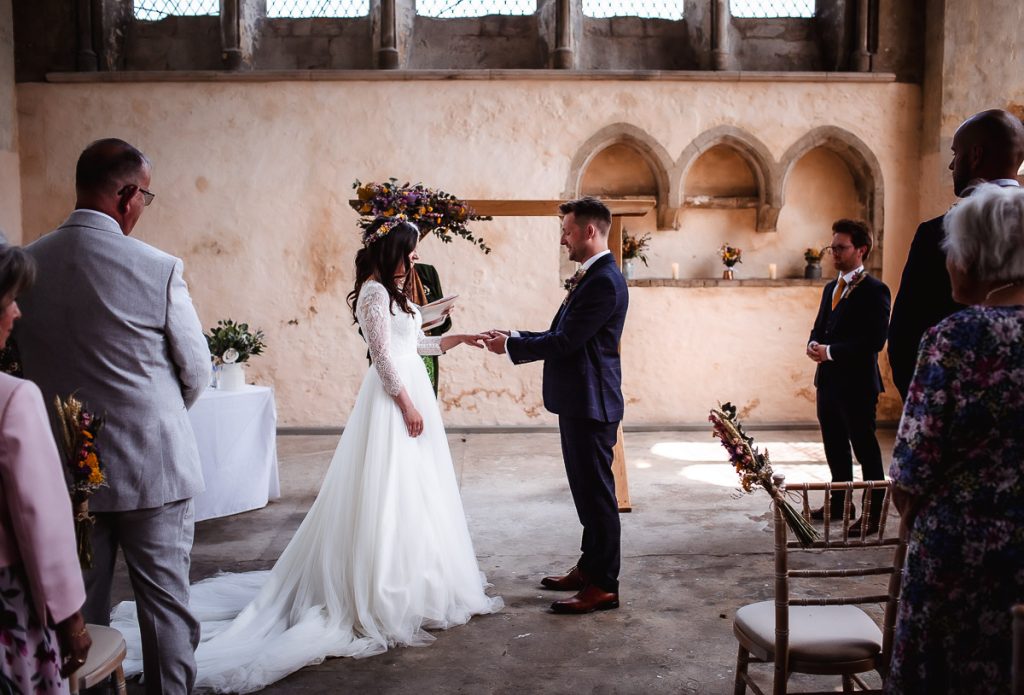 groom is putting a ring on bride's finger at the church during the wedding ceremony in Chichester