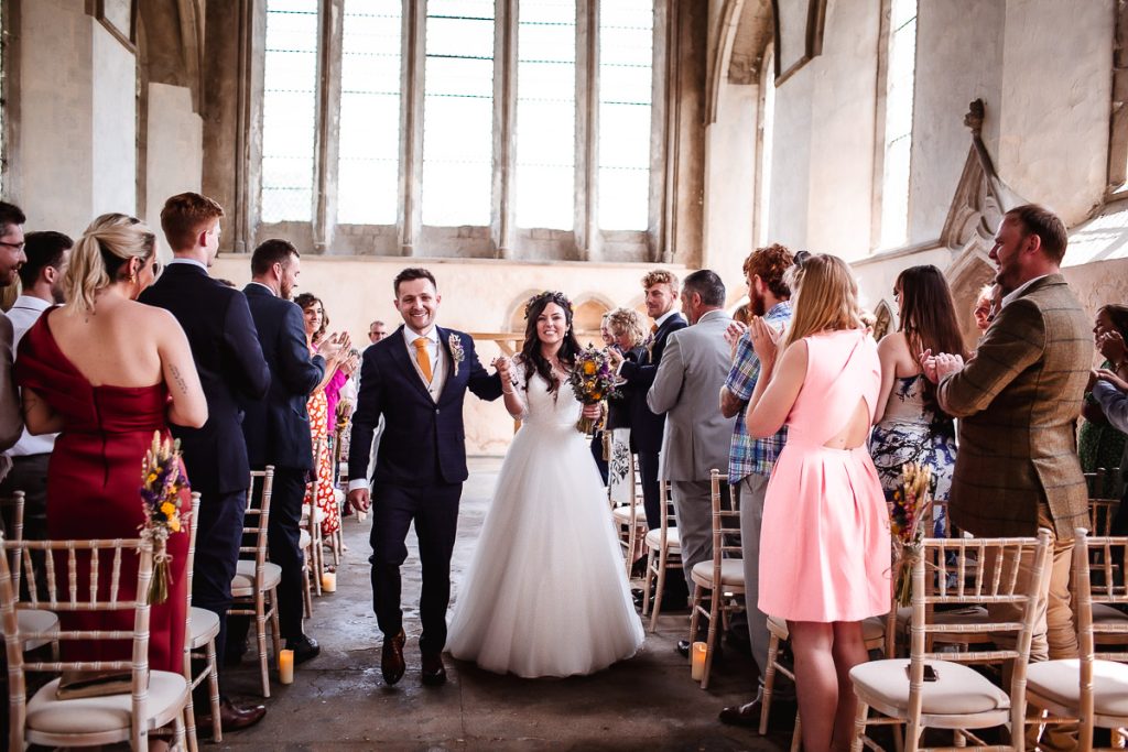 happy bride and groom exiting the aisle with cheering guests at Guildhall, Chichester 