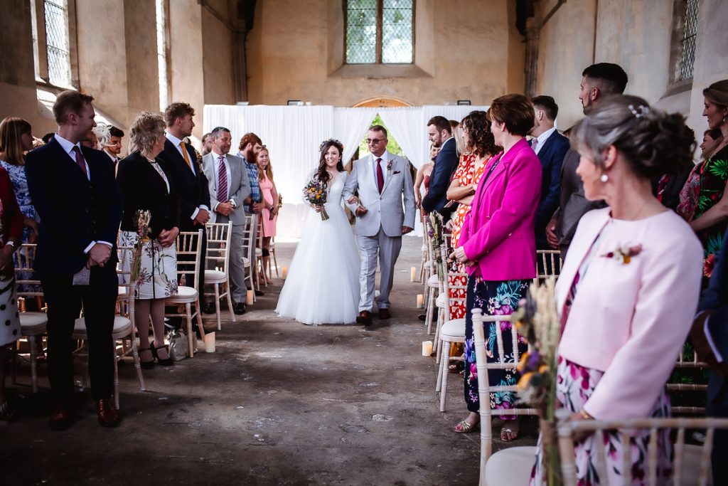 bride is coming down  the aisle with her father at the church Guildhall, Chichester, West Sussex wedding photography