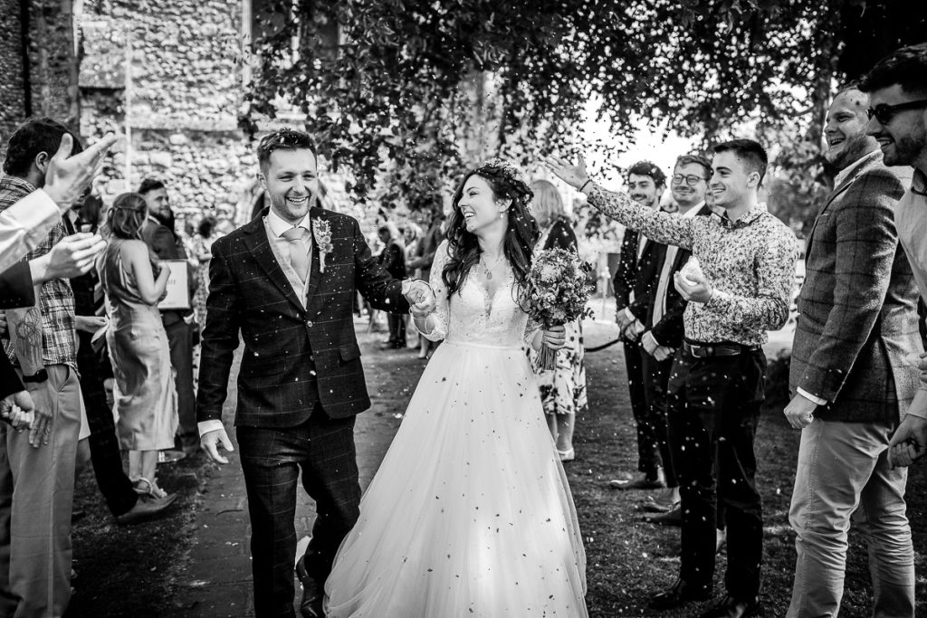 black and white photo of confetti photo of bride and groom by the church