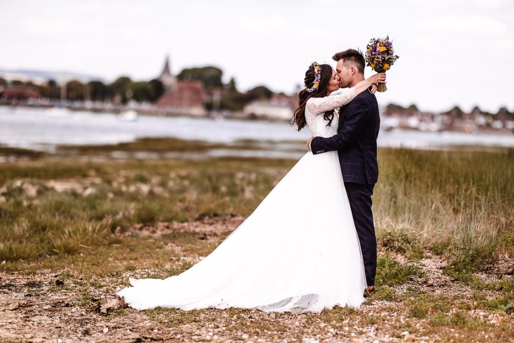 bride and groom kissing by harbour in Bosham. West Sussex wedding photography