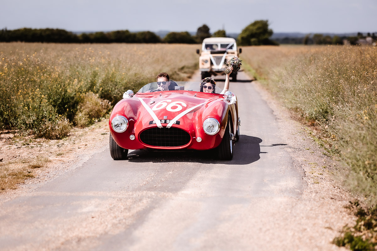 Bride and groom in the red wedding car in West Sussex