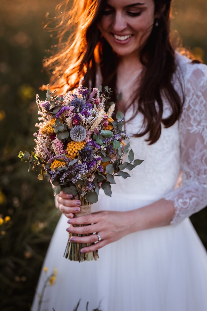 magical sunset photos of bride in the field holding her flowers. Relaxed and natural wedding West Sussex Photographer