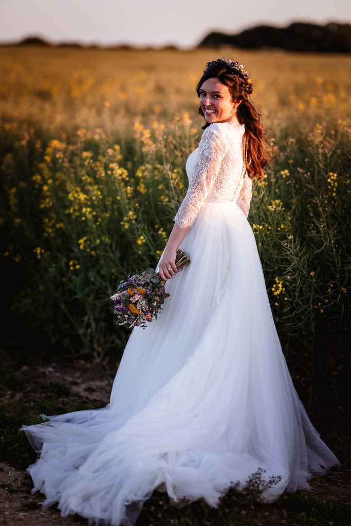 magical sunset photos of bride in the field holding her flowers