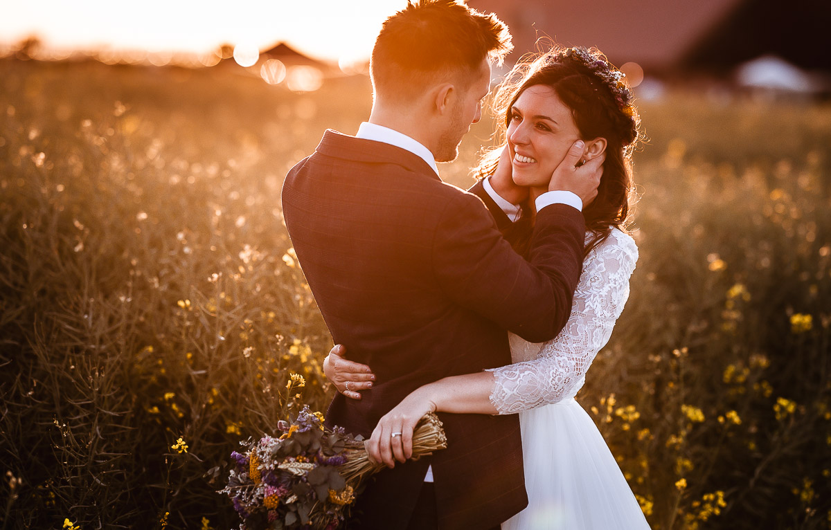 Bride and groom looking at each other in the field during the sunset