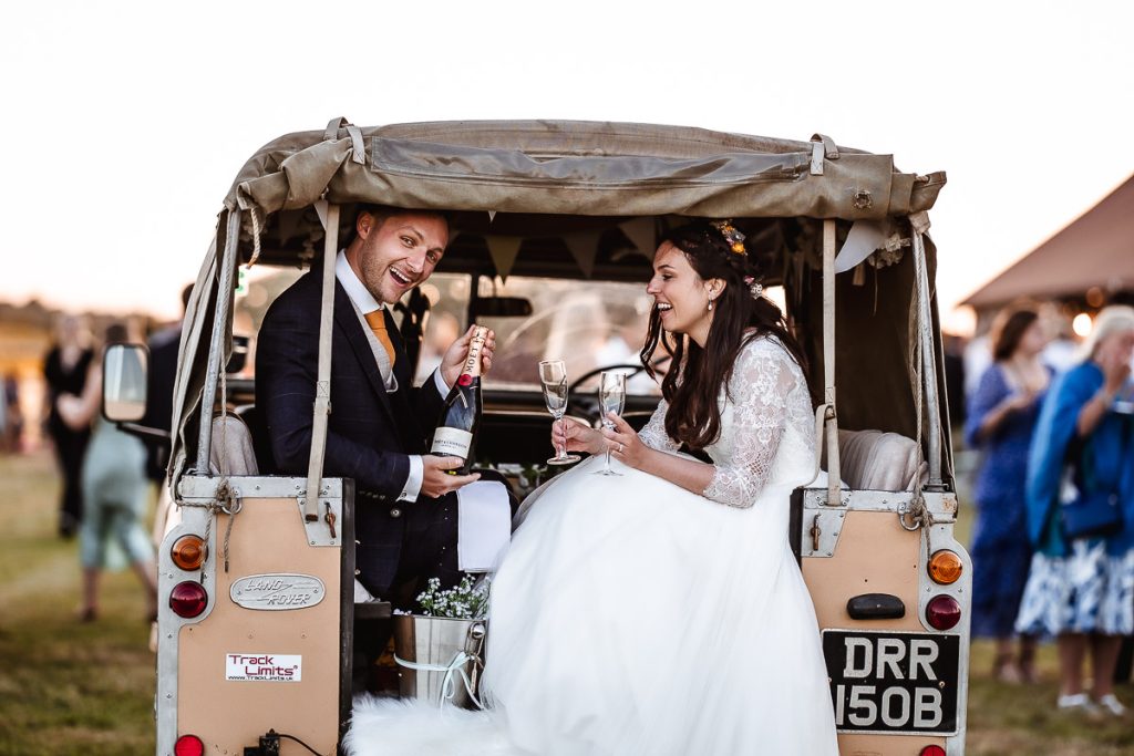 bride and groom having a prosecco in the land rover at Chidham Barn