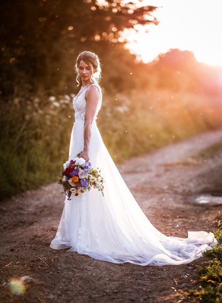 Romantic Sunset photo of bride standing in the field at OXLEAZE BARN COTSWOLD