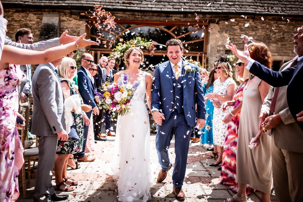 Wedding confetti photo of bride and groom during the outdoor summer ceremony at Oxleaze Barn Cotswold