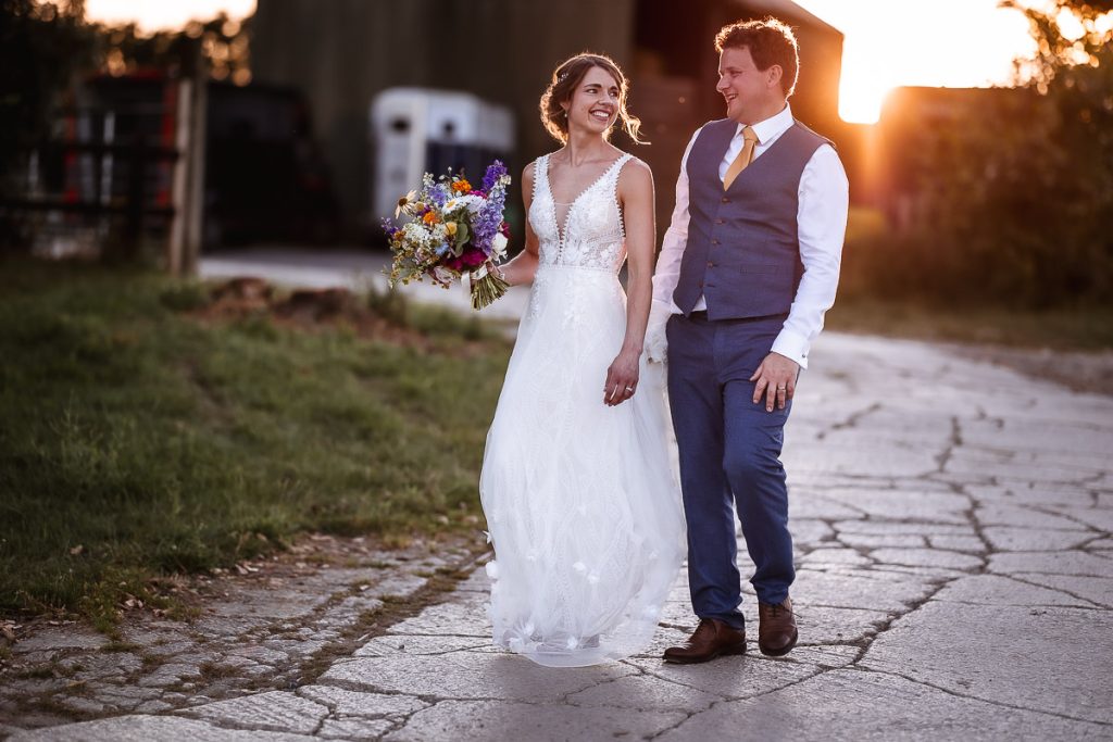 Bride and groom walking together and having a chat during the sunset at Oxleaze Barn, Lechlade, Cotswold