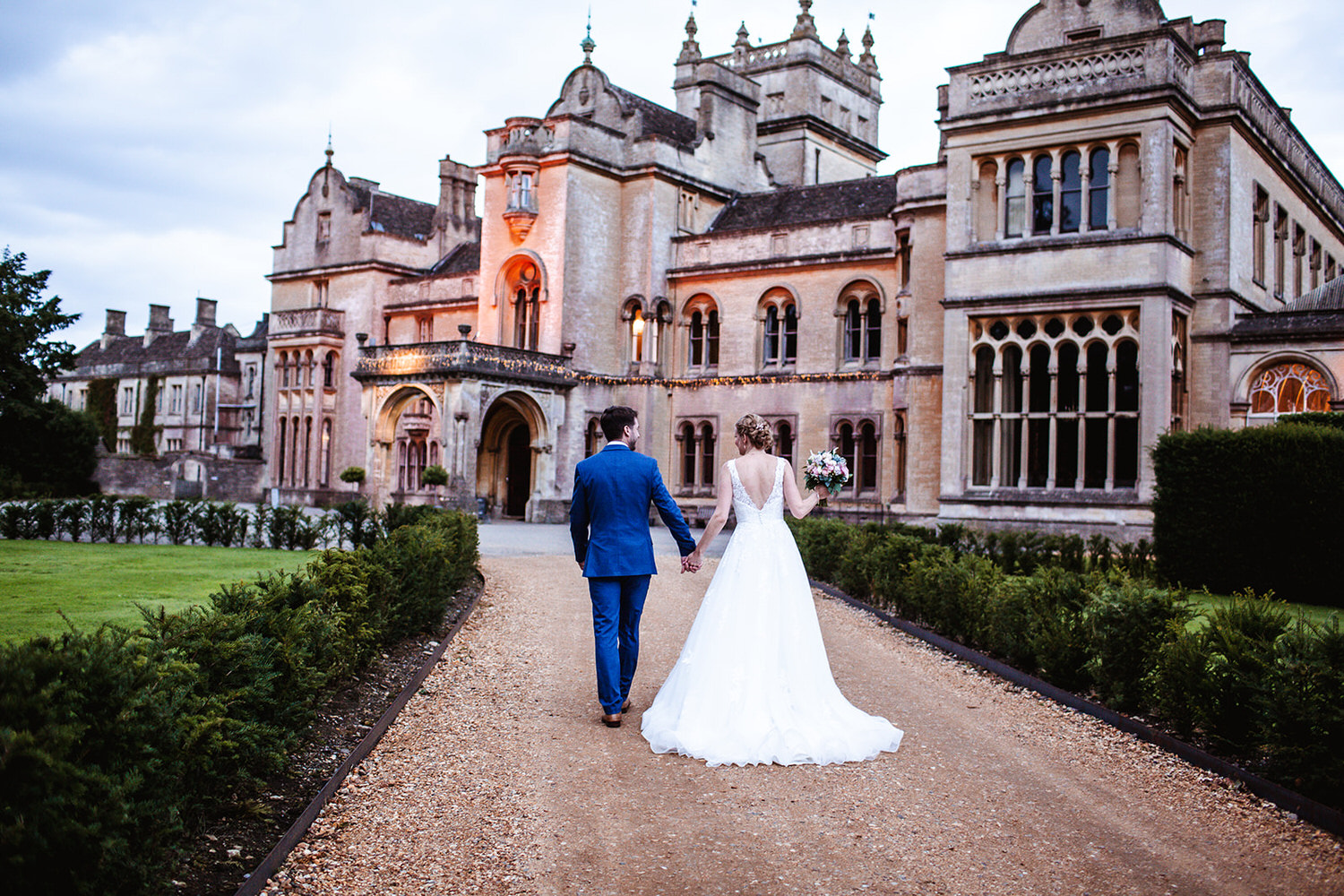 bride and groom walking hand in hand outside their historic and elegant wedding venue at Grittleton House