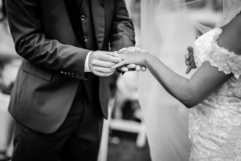 groom is putting a ring on the bride's finger. Outdoor wedding ceremony at Tournerbury Woods