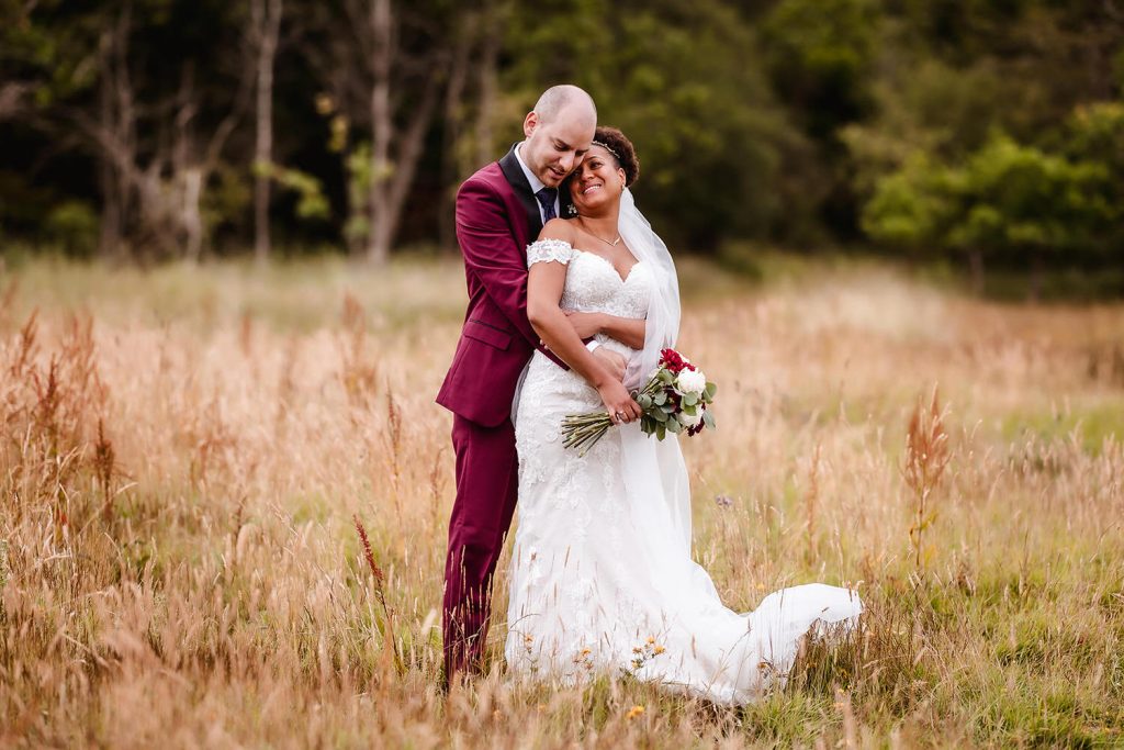 wedding photo of bride and groom standing in the long grass at Tournerbury Woods.