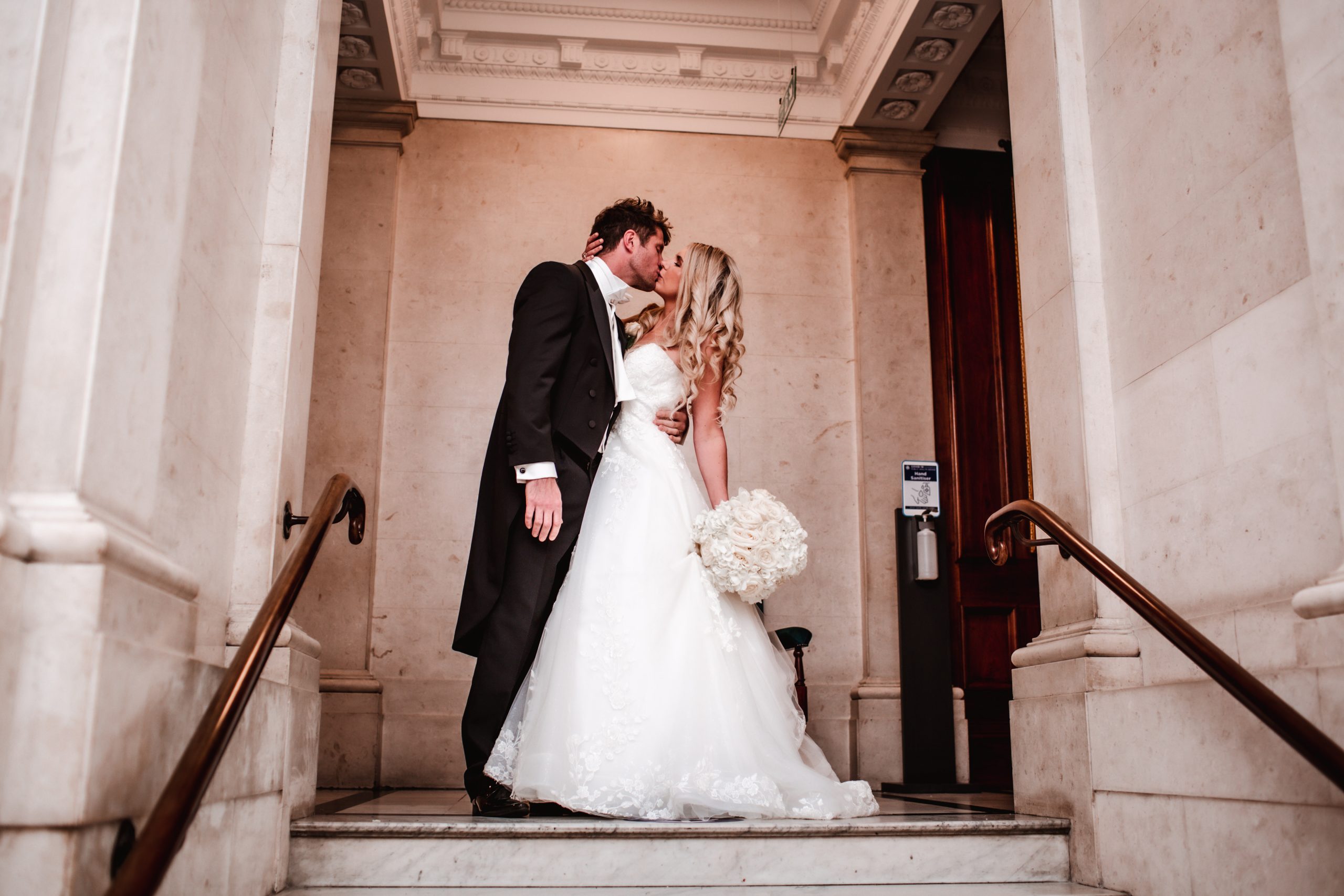 wedding photo of bride and groom kissing by the stairs at Old Marylebone Town Hall in London