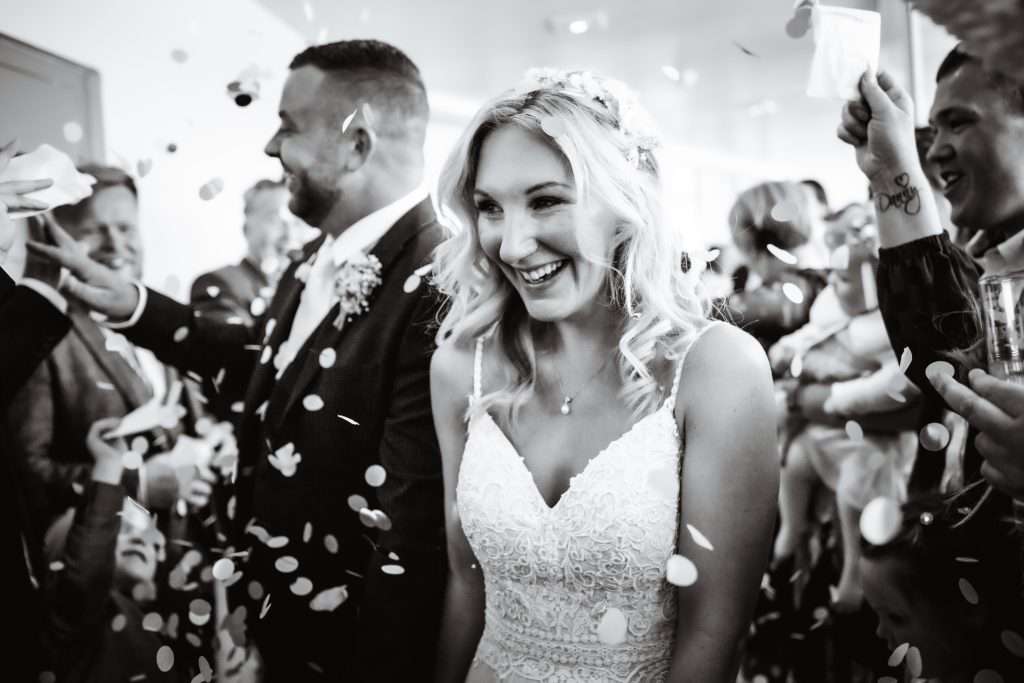 black and white photo of wedding confetti with bride and groom walking down at South Down Manor, Petersfield, Hampshire wedding photography