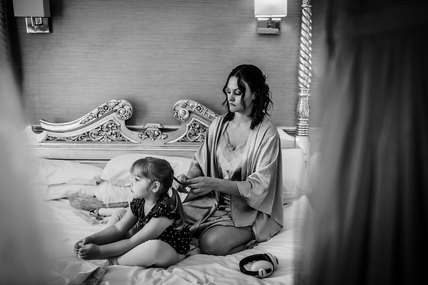 bridesmaid is doing her daughter's hair on a bed. Getting ready photos of bridesmaid and flower girl