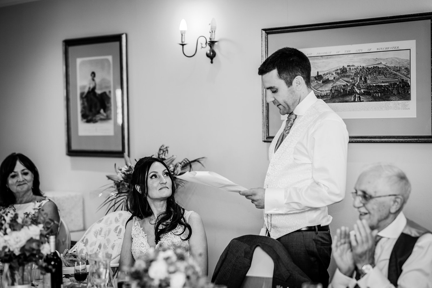 black and white photo of bride and groom during the groom's speech at Winchester Royal Hotel in Chichester