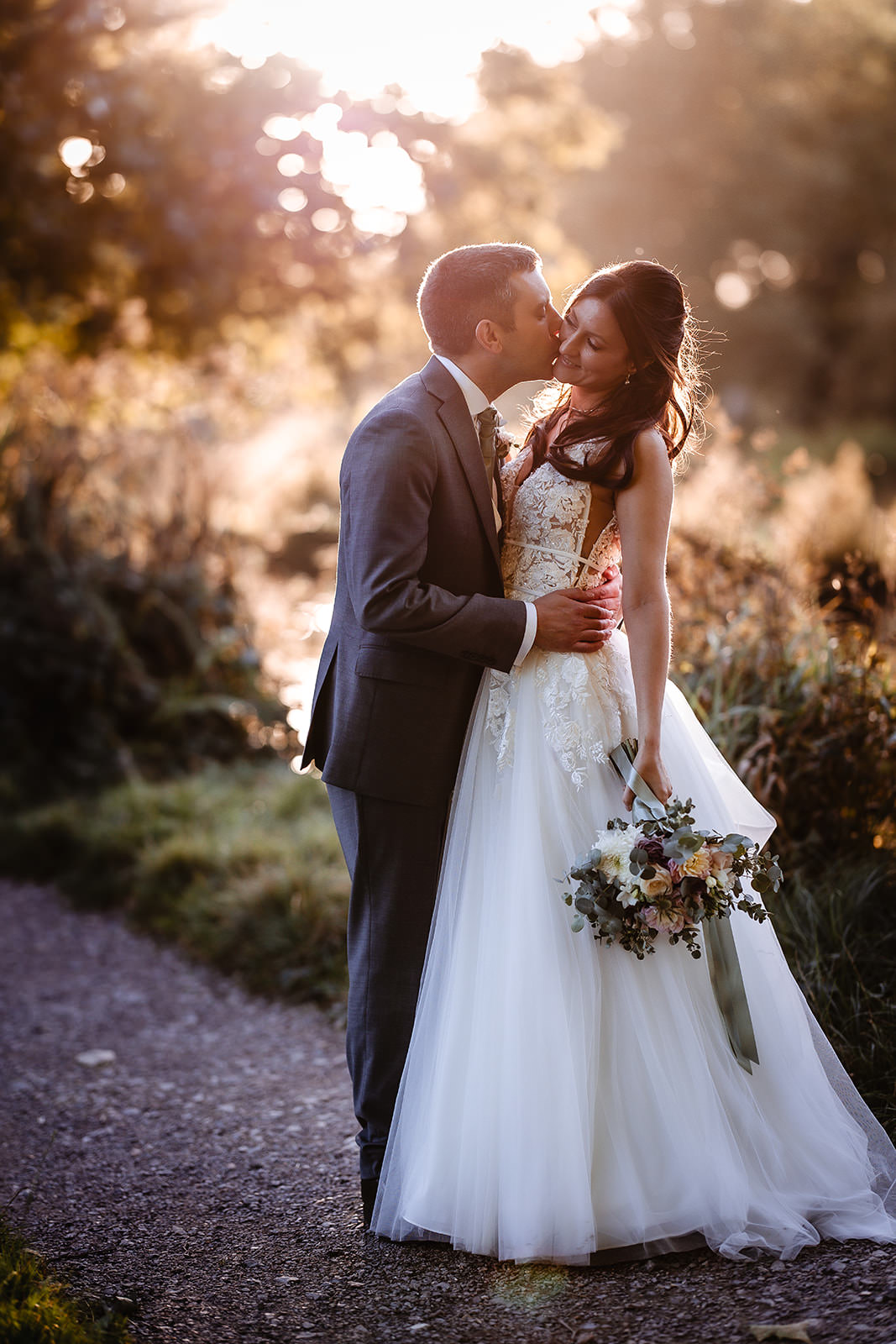 sunset photo of bride and groom kissing by the river in Chichester