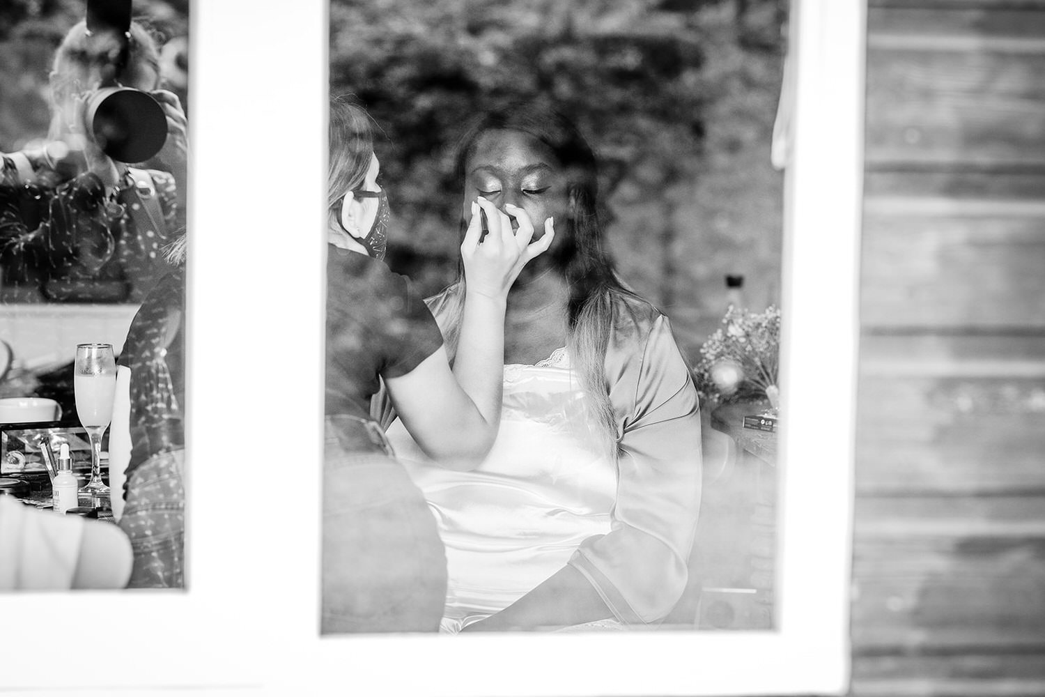 black and white photo of bride putting her make up on before your wedding