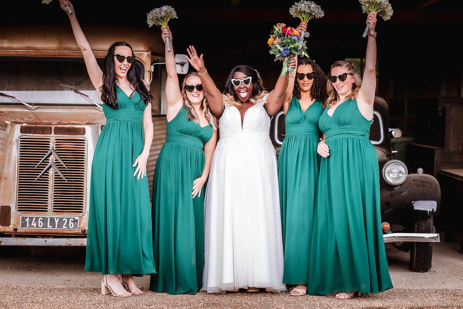 fun photo of bride and her bridesmaids holdiding their flowers up in the air