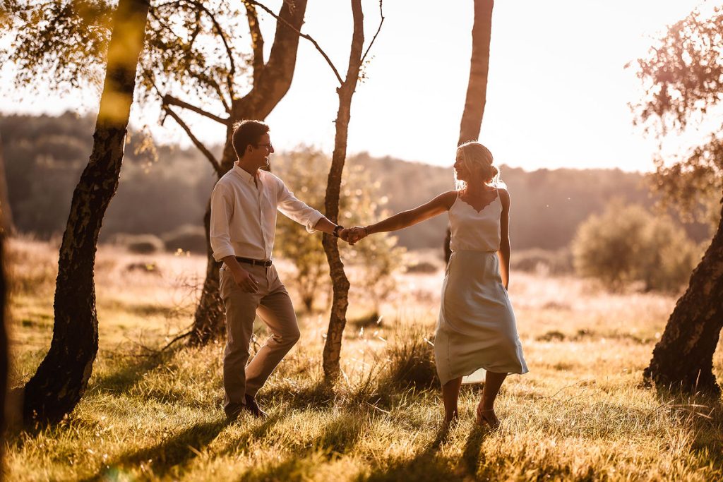 couple walking hand in hand in the forest during the sunset. Hampshire pre wedding and engagement photo session 