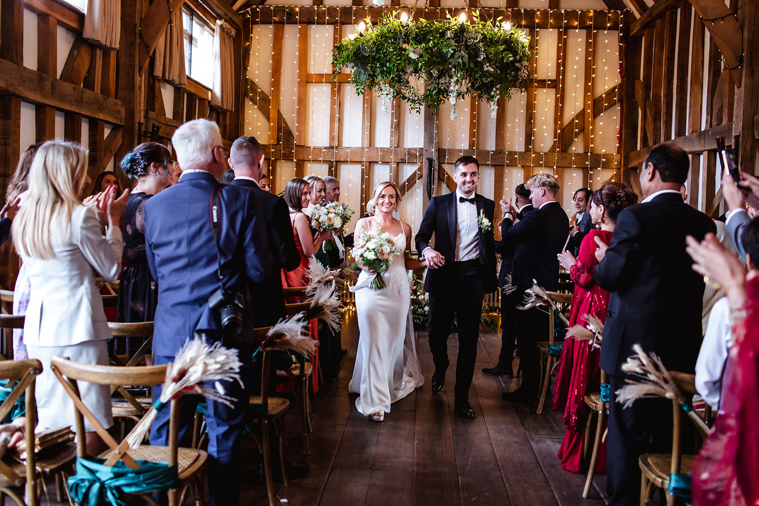 Bride and groom are leaving a wedding ceremony at a rustic barn Street Gate, Guildfor Surrey. Surrey wedding photographer 