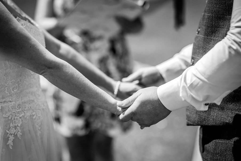 bride and groom holding hand. Details of couple's hands.