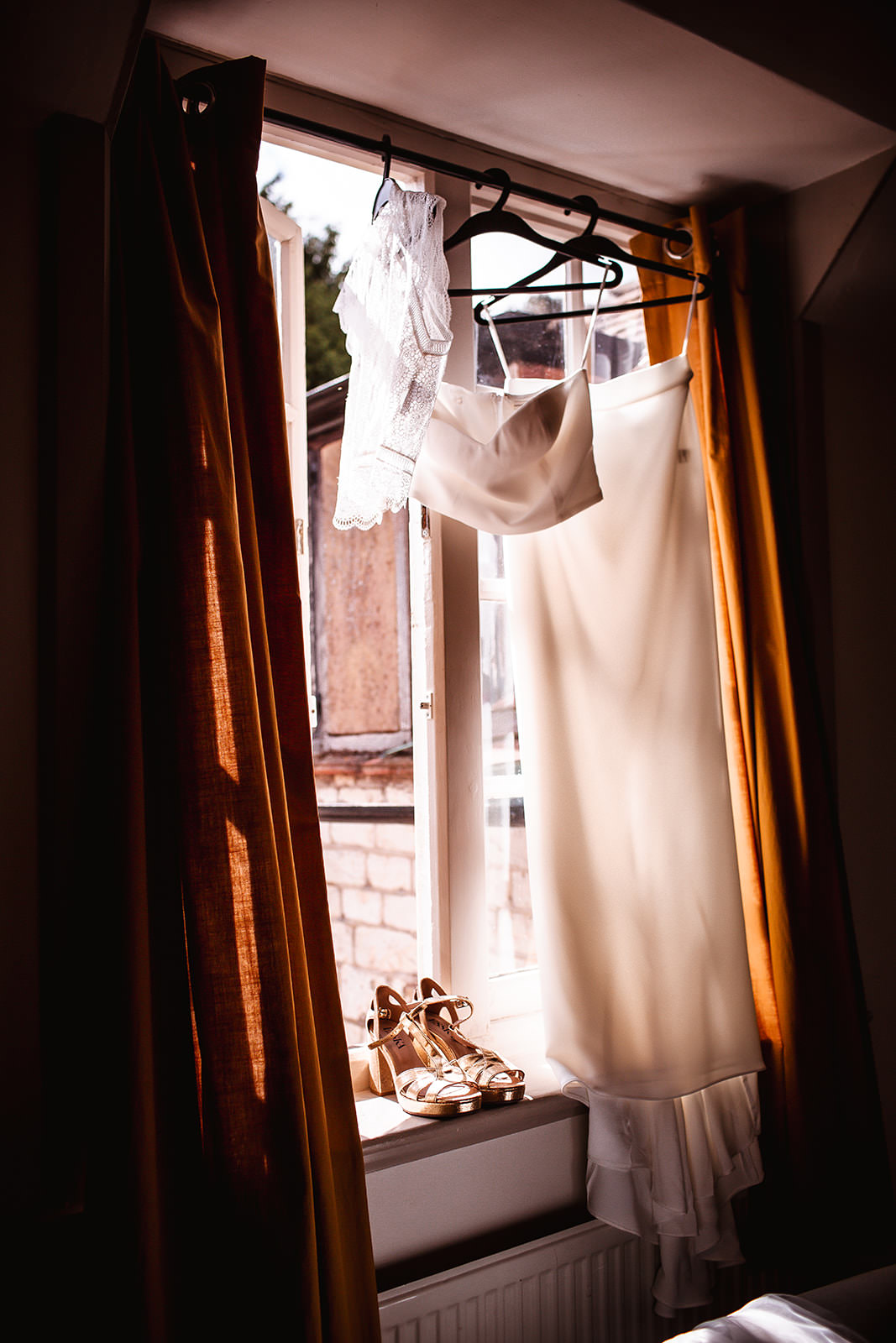 satin wedding dress hanging by the window