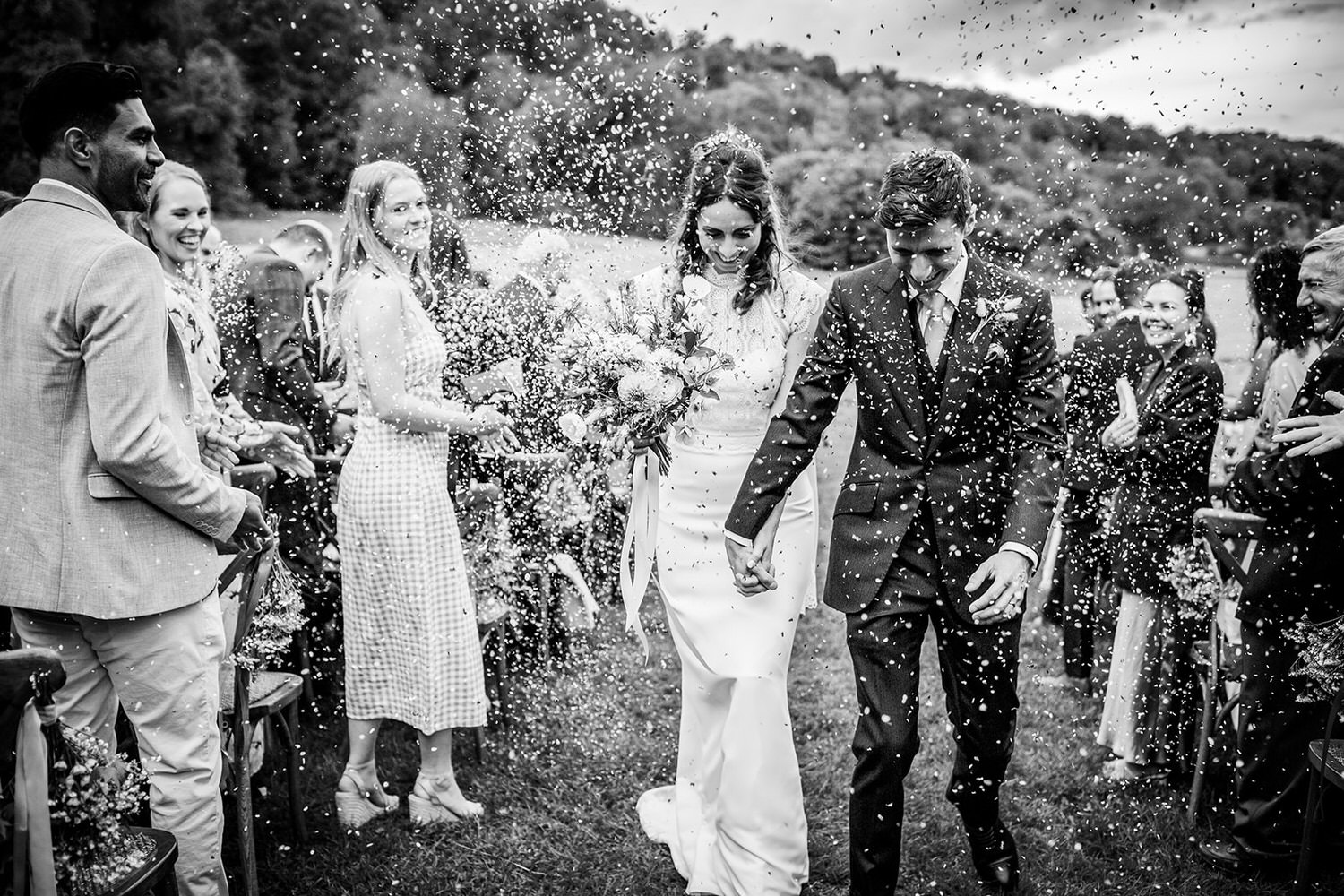 black and white wedding confetti of bride and groom leaving the ceremony