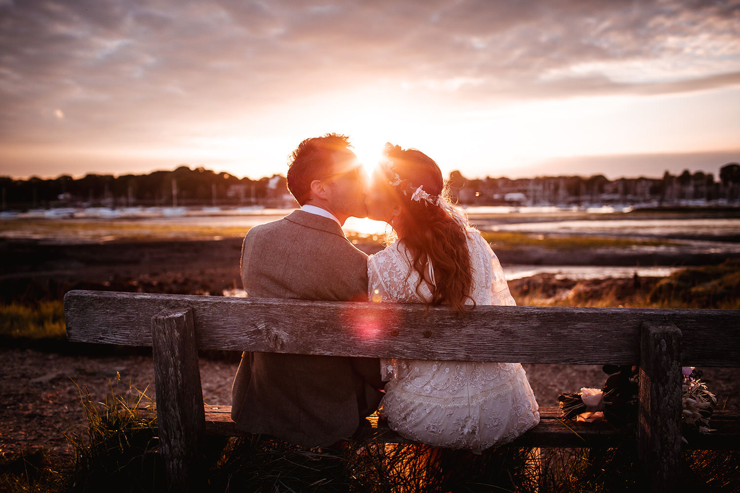 sunset photo of bride and groom kissing on the bench at the harbour in Southhampton