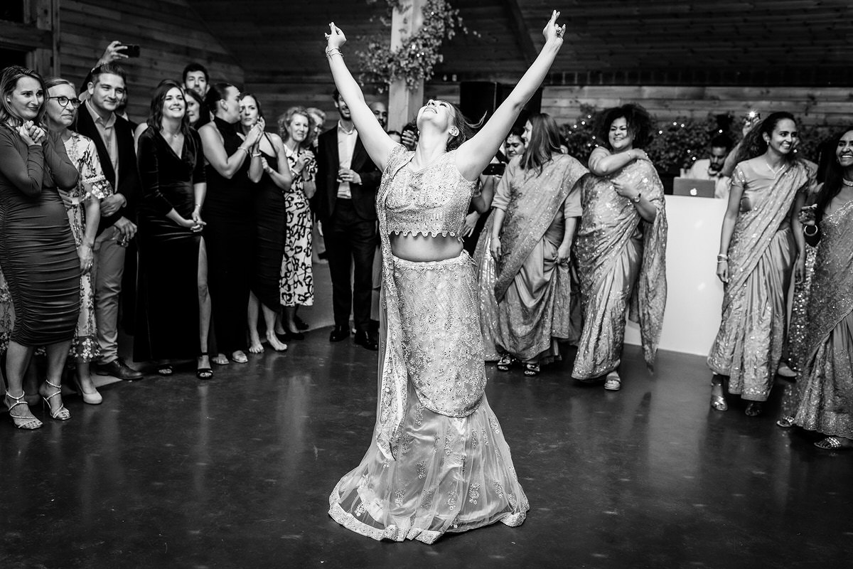 bride is dancing a surprised Indian dance for her groom