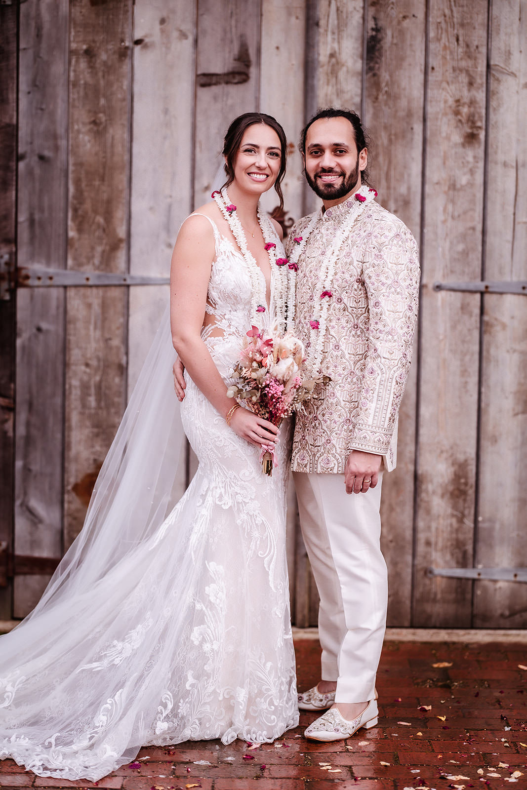 bride and groom standing together by the rustic barn. Indian wedding couple