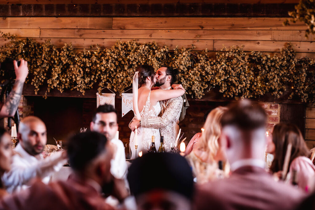 bride and groom kissing at the table during the wedding reception