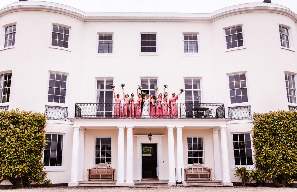 Bride with bridesmaids are cheering from the balcony of the wedding venue