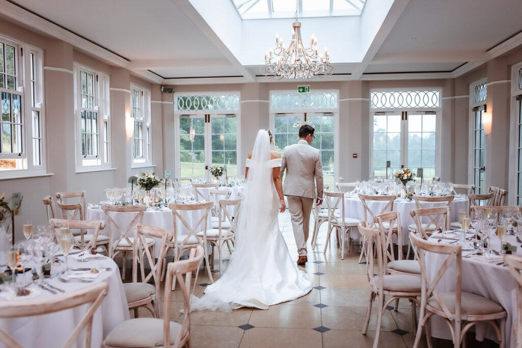 bride and groom walking in to the reception room to check the table and wedding decoration