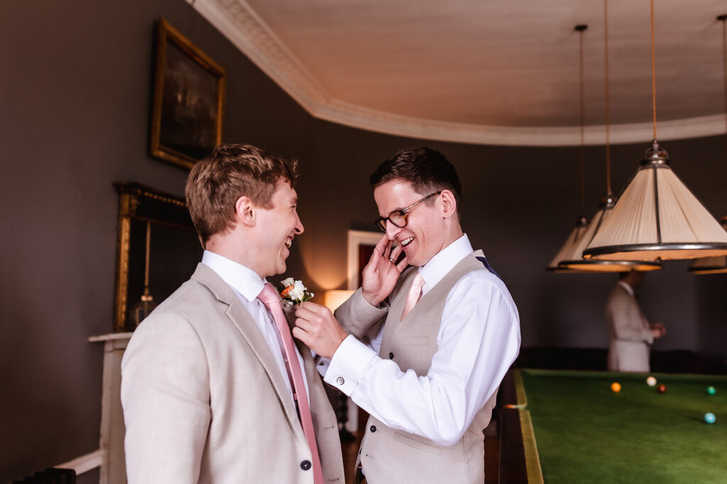 groom is putting a tie on his best man