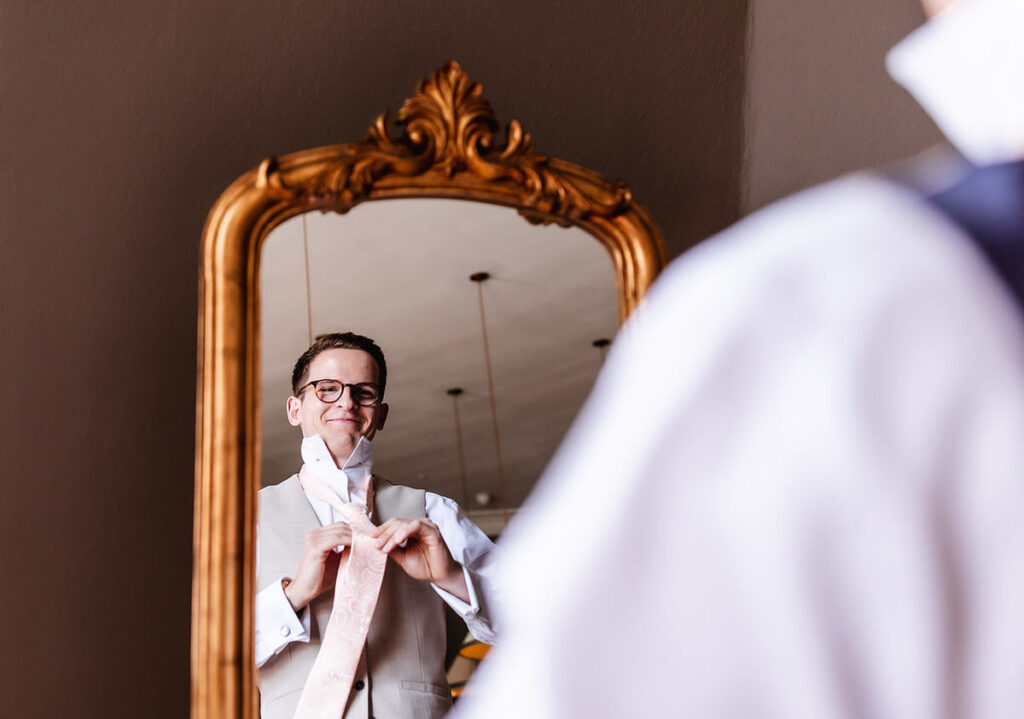 groom is putting his tie on and getting ready for his wedding