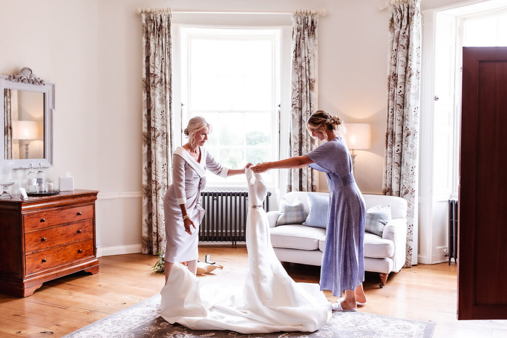 mother is helping her daughter to get dress on her wedding day