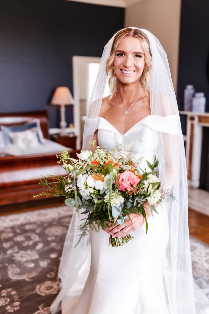 happy and smiling bride in her wedding dress holding her flowers/bouquet