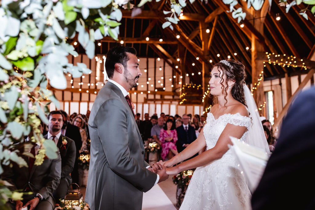 bride and groom holding hands at the rustic barn during the ceremony