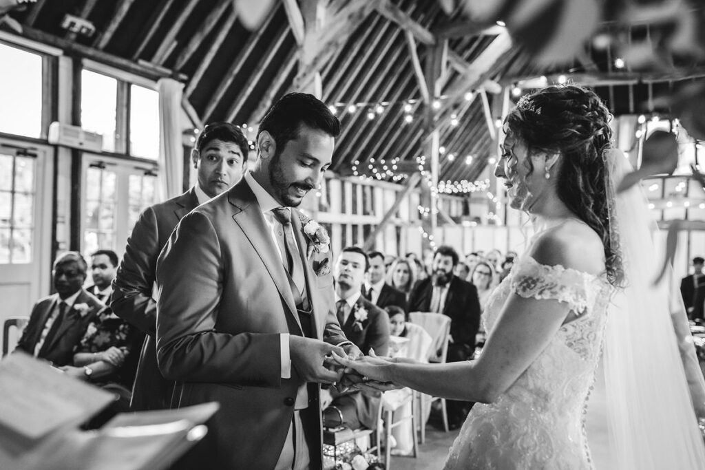 groom is putting a wedding ring on bride's finger