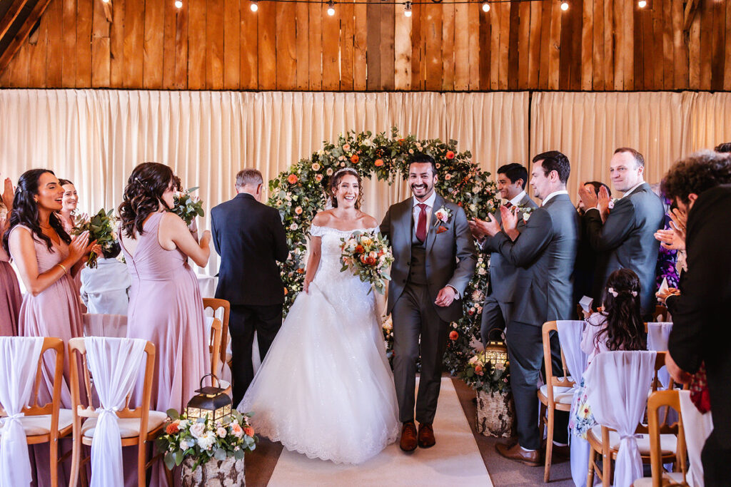 bride and groom are leaving the wedding ceremony with guests clapping and cheering