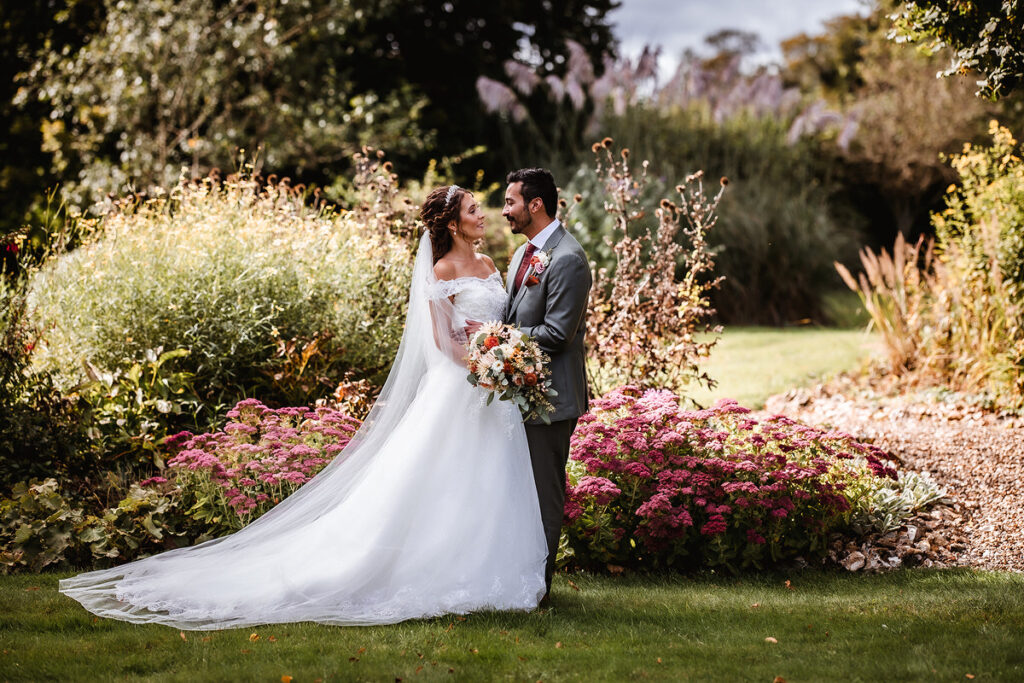 landscape photo of bride and groom looking at each other in the garden 