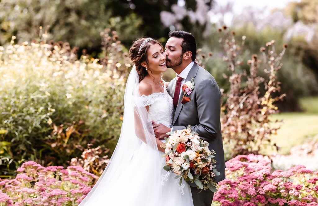 romantic wedding photo of groom kissing his bride on her cheek 