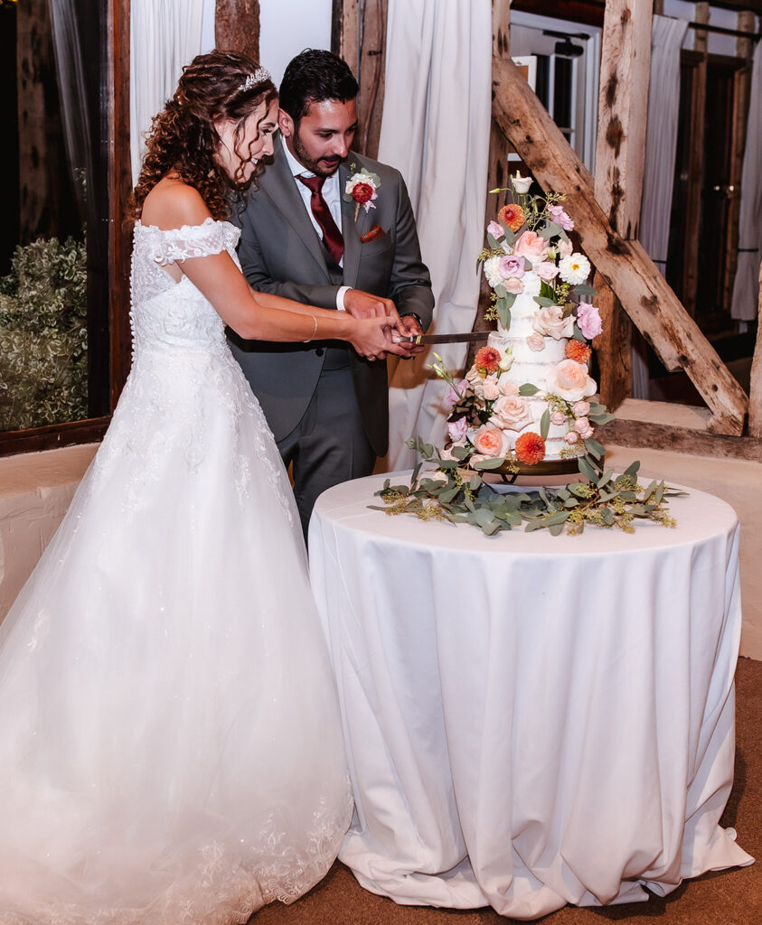 bride and groom cutting a big five tire wedding cake with flower decoration